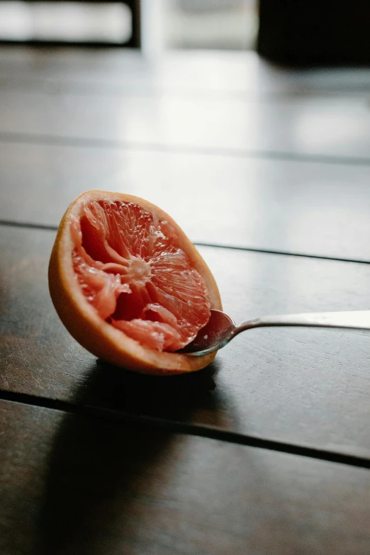 a gfruit cut in half and being held with a spoon