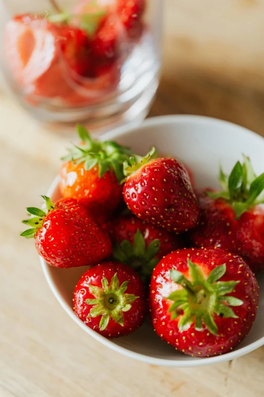 a bowl of strawberries sitting on top of a wooden table