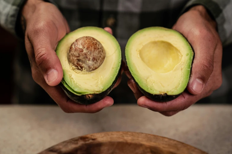 a person holding two halves of an avocado, a portrait, by Dan Content, trending on pexels, subtle detailing, chilean, a middle-shot from front, recipe