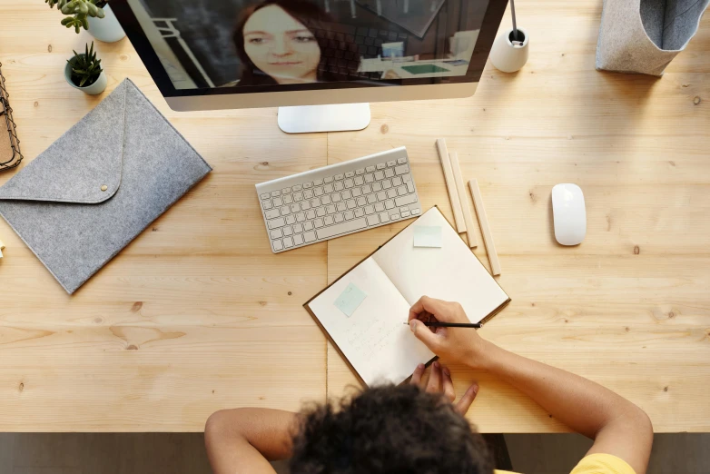 a man sitting at a desk in front of a computer, a picture, by Julia Pishtar, trending on pexels, writing in journal, bottom angle, webcam footage, school class