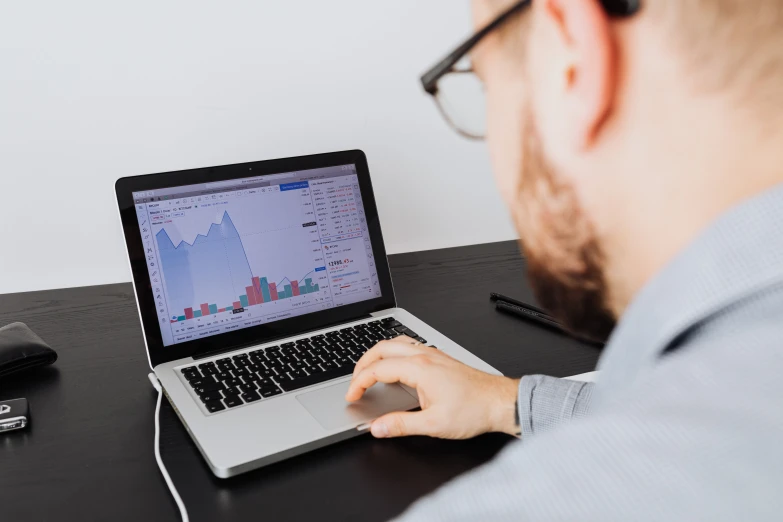 a man sitting at a desk using a laptop computer, a picture, trending on unsplash, analytical art, graph signals, plain background, trading stocks, low quality photo