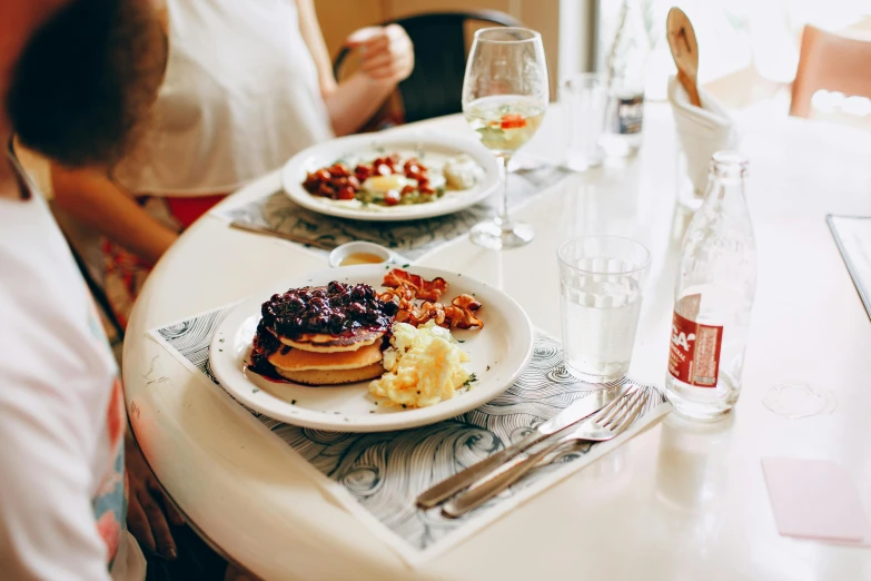 a couple of people sitting at a table with plates of food, by Carey Morris, pexels contest winner, living food adorable pancake, at noon, gif, shiny and sparkling