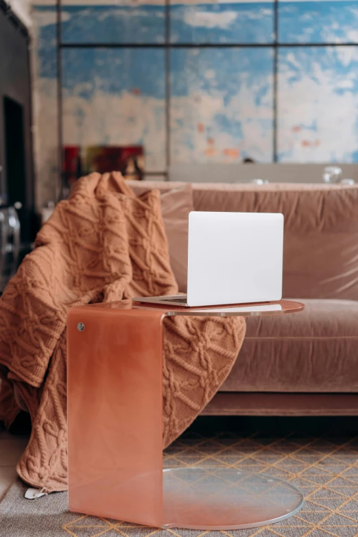 a laptop computer sitting on top of a wooden table, by Daniel Gelon, trending on pexels, modernism, velvet couch, covered with blanket, brown, full-body