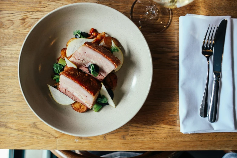 a plate of food sitting on top of a wooden table, inspired by Richmond Barthé, unsplash, pork, elegantly dressed, half turned around, crisp lines