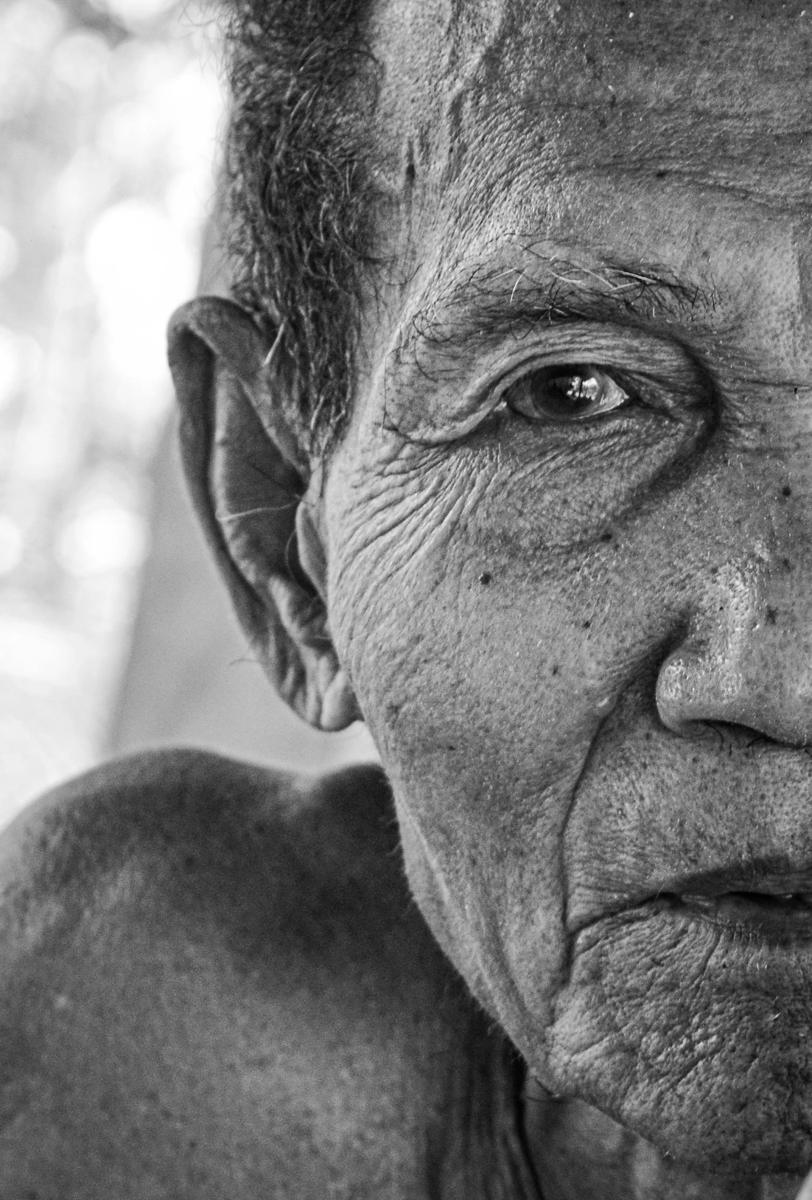 a black and white photo of an old man, photorealism, indigenous man, focus on facial features, older woman, closeup shot of face