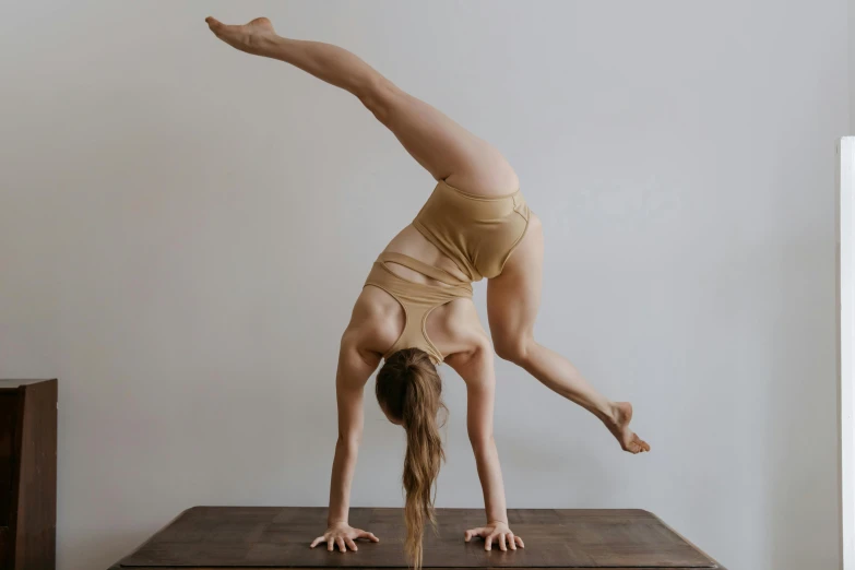 a woman doing a handstand on a wooden table, unsplash, arabesque, low quality photo, sculpted, wearing leotard, anthro