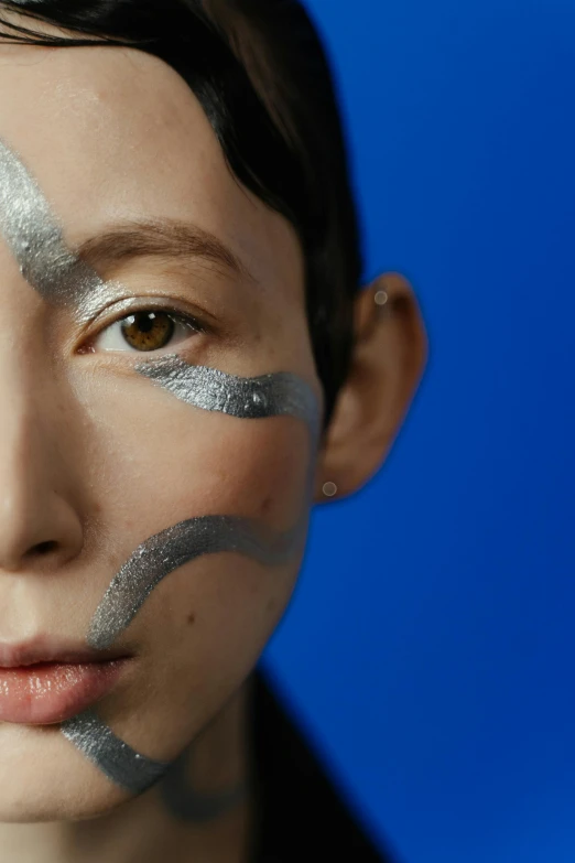 a close up of a person with silver paint on their face, an album cover, inspired by Gao Cen, smooth blue skin, shot with sony alpha, genderless, portrait of a japanese teen