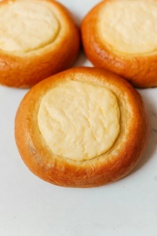 a close up of three pastries on a plate, inspired by Kanō Shōsenin, made of swiss cheese wheels, round round round nose, 王琛, flan