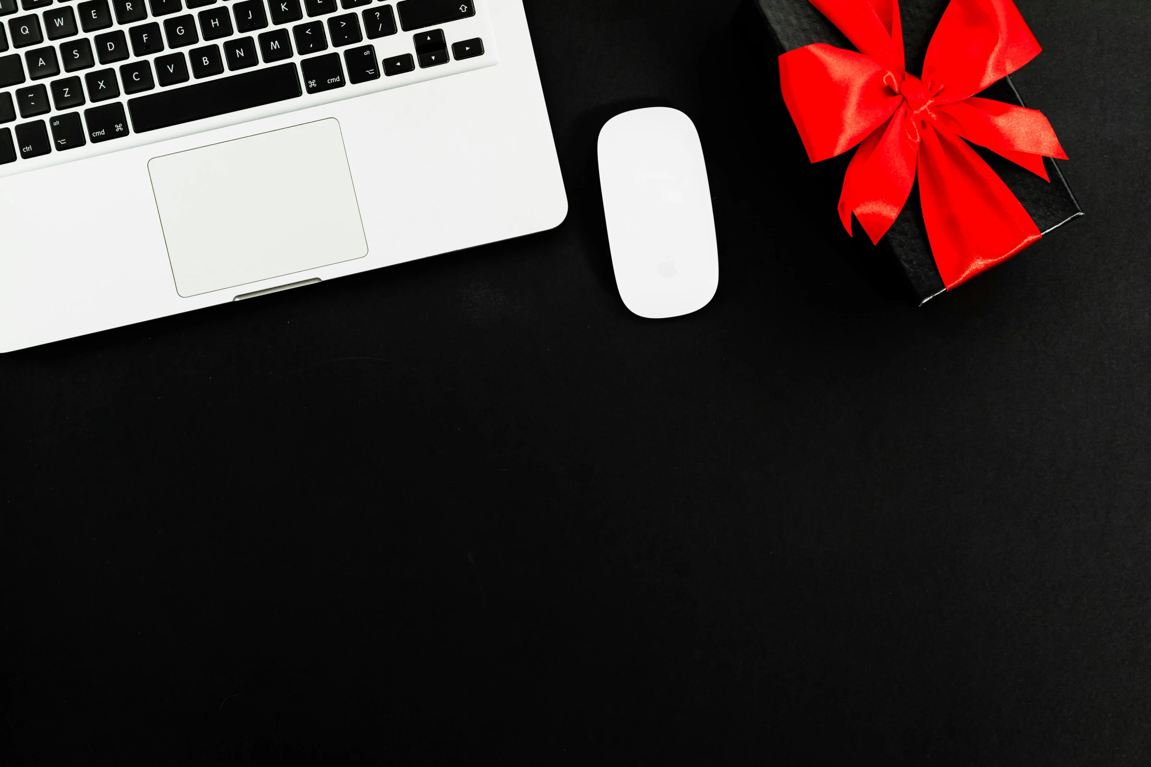 a laptop computer sitting on top of a desk next to a mouse, by Julia Pishtar, pexels contest winner, giving gifts to people, white on black, background image, holiday