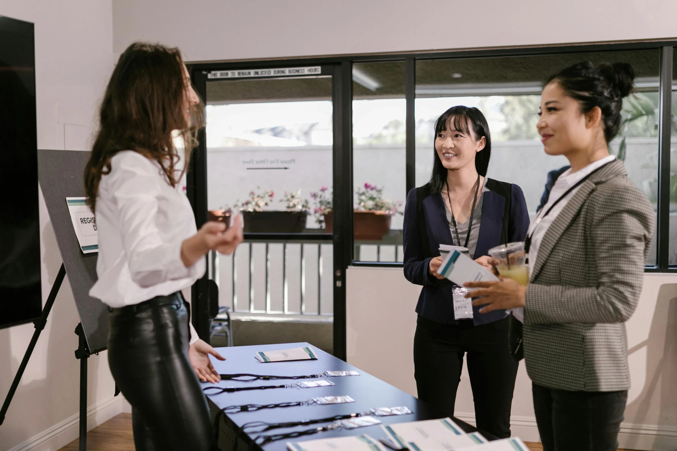 a group of women standing around a table, unsplash, wearing business casual dress, asian female, colour print, selling insurance