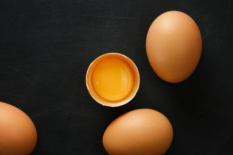 a group of eggs sitting on top of a table, dark backdrop, detailed product image, essence, full product shot