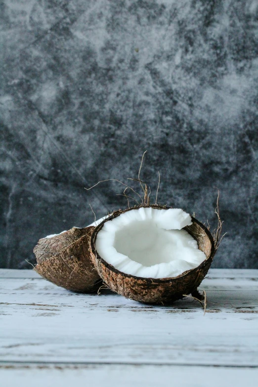 a half eaten coconut sitting on top of a wooden table, a portrait, unsplash, on a gray background, decorative, made of glazed, warm