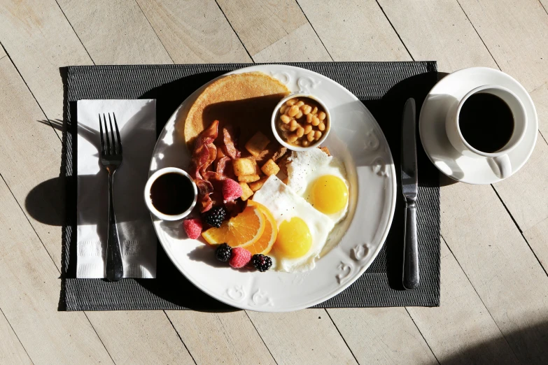 a white plate topped with breakfast food next to a cup of coffee, full sun, offering a plate of food, eggs, plates of fruit