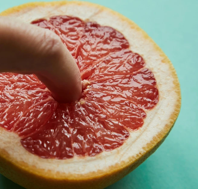 a close up of a person touching a grapefruit, by Julian Allen, bump in form of hand, fleshy musculature, epicurious, taken in the early 2020s