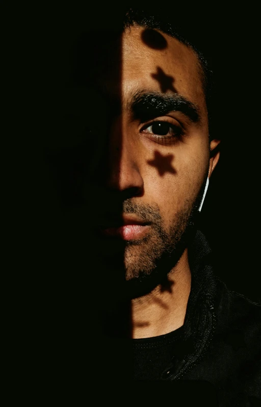 a man with a cross painted on his face, an album cover, inspired by Ahmed Yacoubi, pexels contest winner, hurufiyya, occlusion shadow, ( ( theatrical ) ), light from right, half portrait