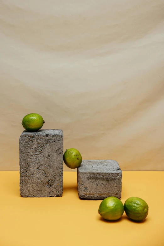 limes and concrete blocks on a yellow surface, inspired by Isamu Noguchi, textured base ; product photos, lulu chen, tall structures, promo photo