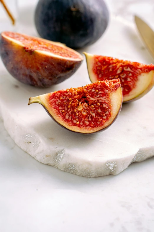 a couple of figs sitting on top of a cutting board, a marble sculpture, speckled, white, reds, golden