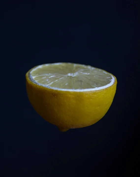 a half of a lemon sitting on top of a table, a macro photograph, unsplash, standing with a black background, no watermark, medium format, detailed product image