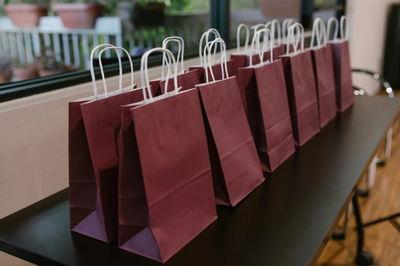 a row of bags sitting on top of a table, maroon and white, birthday party, unopened, thumbnail