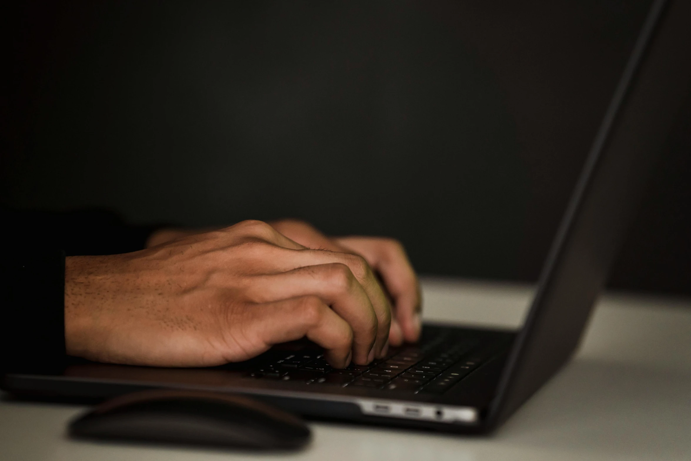 a close up of a person typing on a laptop, by Carey Morris, pexels, computer art, a man wearing a black jacket, brown, low-light, menacing