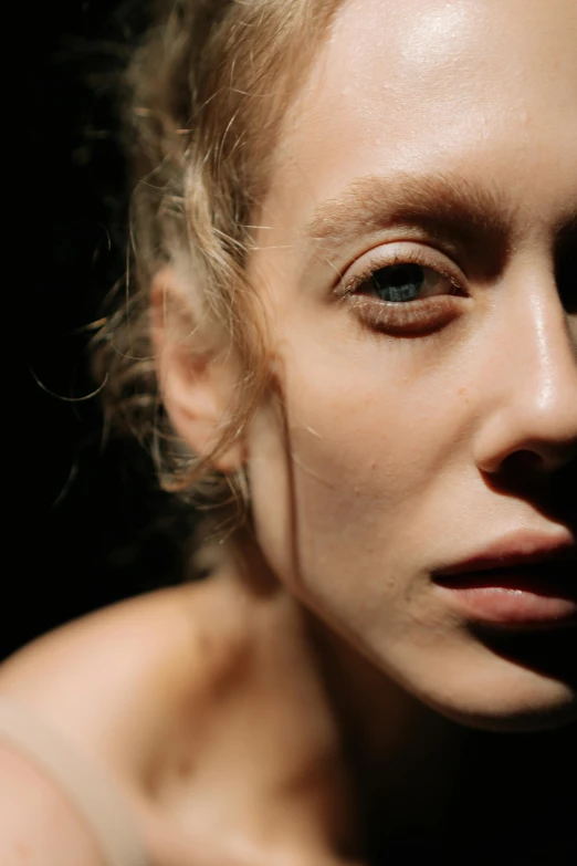 a woman standing in front of a black background, inspired by Nan Goldin, hyperrealism, close up of a blonde woman, sunbathed skin, angela sarafyan, ignant