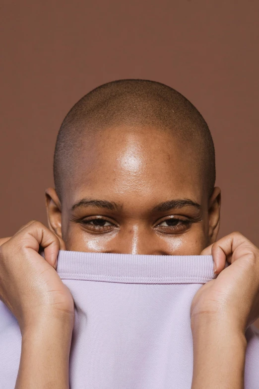 a close up of a person holding a shirt over their face, by Cosmo Alexander, no hair completely bald, alexis franklin, lovingly looking at camera, solid background