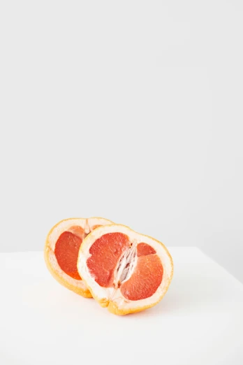 a grapefruit cut in half on a white surface, by Gavin Hamilton, unsplash, jen atkin, made of glazed, medium format. soft light, modern minimalist f 2 0