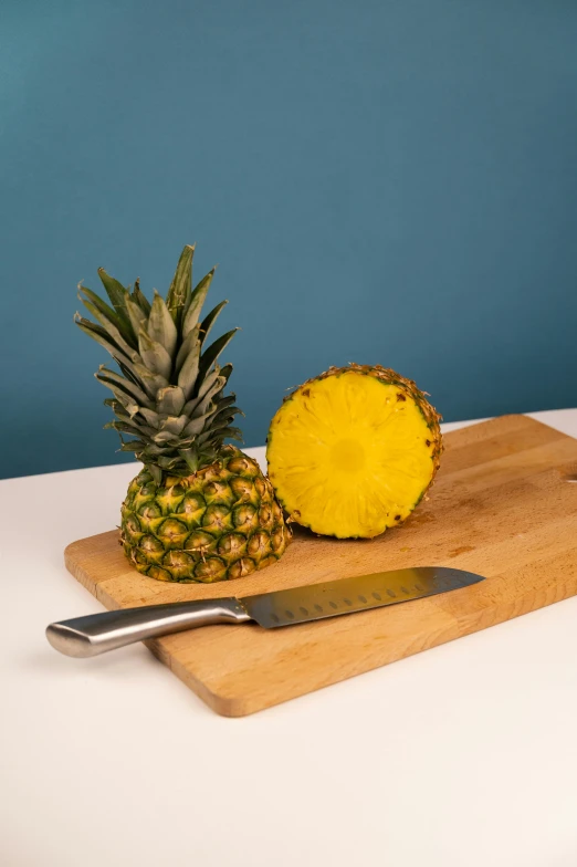 a pineapple and a knife on a cutting board, sitting on a table, detailed product image, grey, medium shot angle