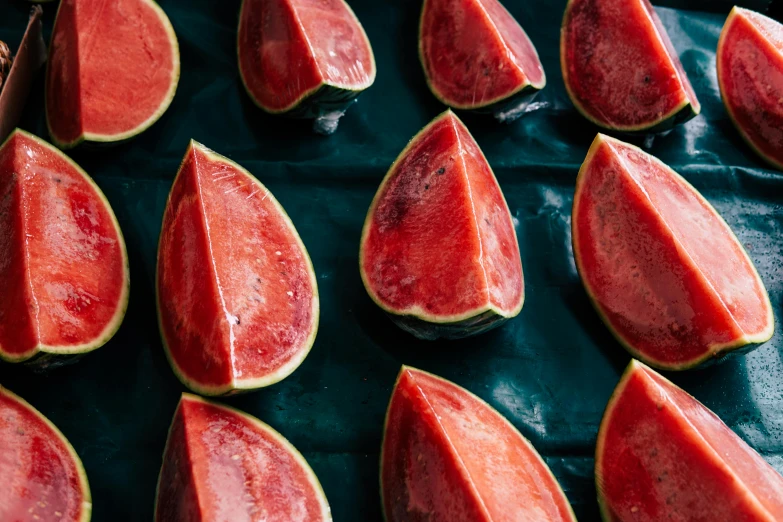 a bunch of slices of watermelon on a table, a photo, by Julia Pishtar, trending on pexels, art nouveau, background image, in a row, red velvet, 2000s photo