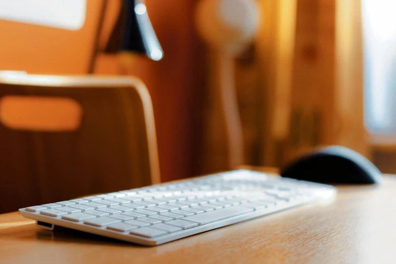 a computer keyboard sitting on top of a wooden desk, by Carey Morris, trending on pexels, sitting across the room, portrait of small, thumbnail, in the evening