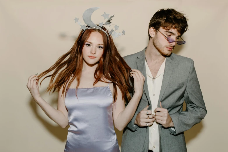 a man and a woman standing next to each other, an album cover, by Daphne McClure, trending on pexels, renaissance, sophie turner girl, with haunted eyes and glasses, wearing a paper crown, moon shine