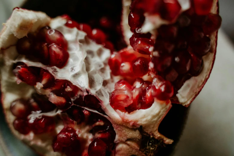 a close up of a pomegranate on a plate, trending on pexels, process art, berries inside structure, crushed, dark and white, 🦩🪐🐞👩🏻🦳