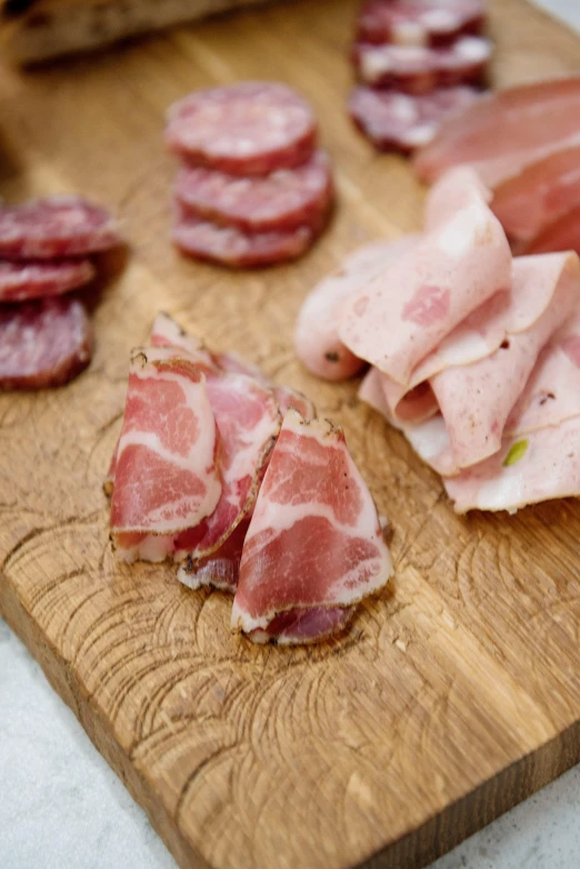 a wooden cutting board topped with slices of meat, caulicoli, piglet, grey, scottish