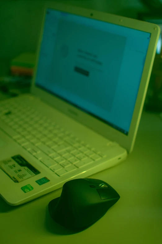 a white laptop computer sitting on top of a desk, flickr, ambient green light, low quality photo, mouse photo, hacking