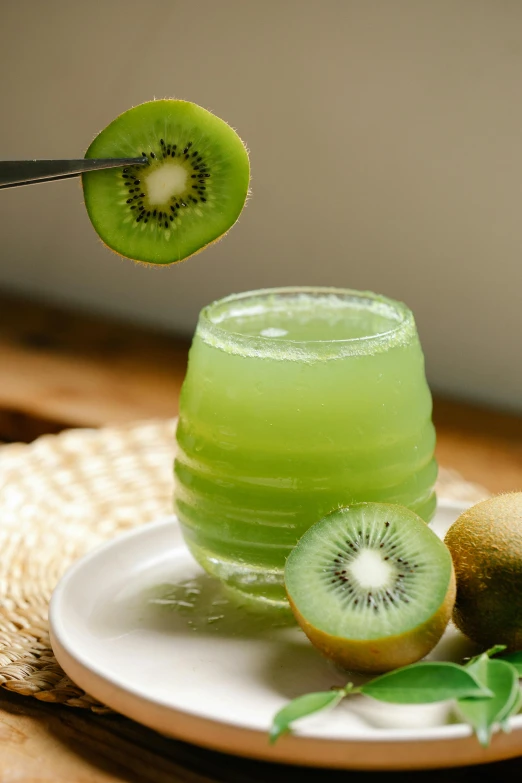 a green drink sitting on top of a white plate, inspired by Kanō Tan'yū, hurufiyya, kiwi fruit, te pae, cut, cheery