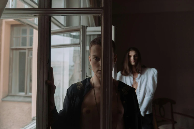 a man standing in front of a window next to a woman, a picture, inspired by Elsa Bleda, pexels contest winner, bauhaus, menacing pose, frank dillane as puck, maxim shirkov, demons