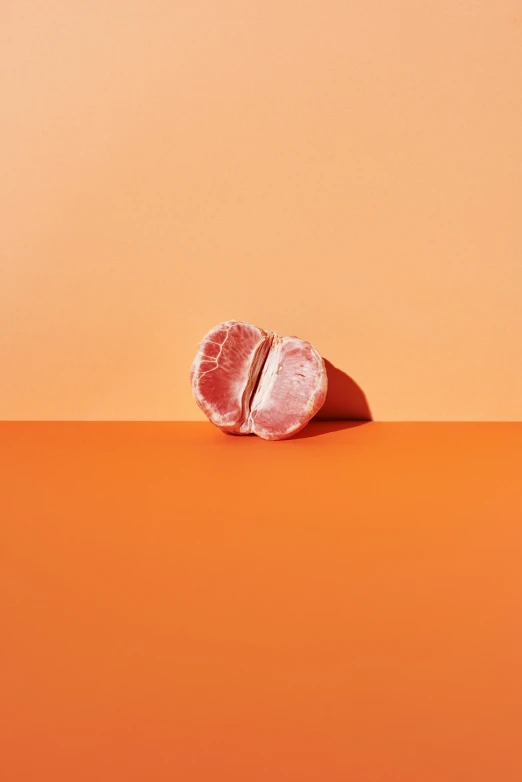a piece of meat sitting on top of an orange surface, by Tobias Stimmer, split in half, shot on hasselblad, rinko kawaichi, plain background