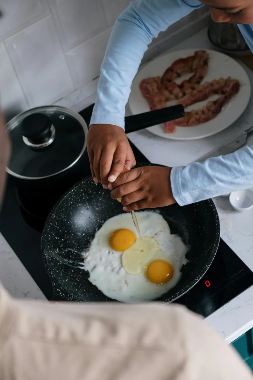 a man cooking eggs in a frying pan on a stove, by Adam Marczyński, pexels contest winner, close together, bacon, malaysian, 15081959 21121991 01012000 4k