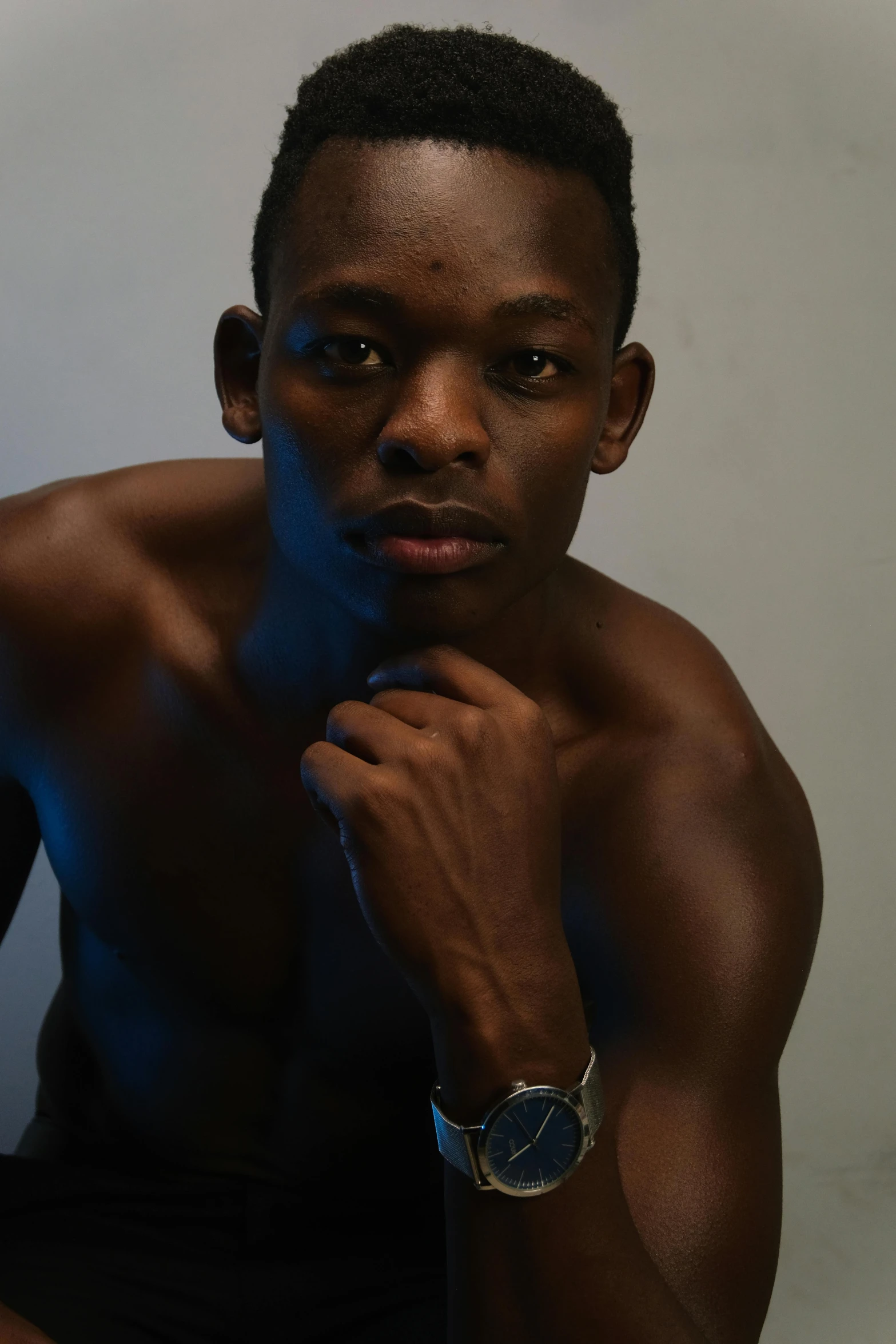 a man that is sitting down with his hand on his chin, an album cover, inspired by David Bailly, pexels contest winner, hyperrealism, showing off his muscles, ( ( dark skin ) ), model standing pose, thin young male