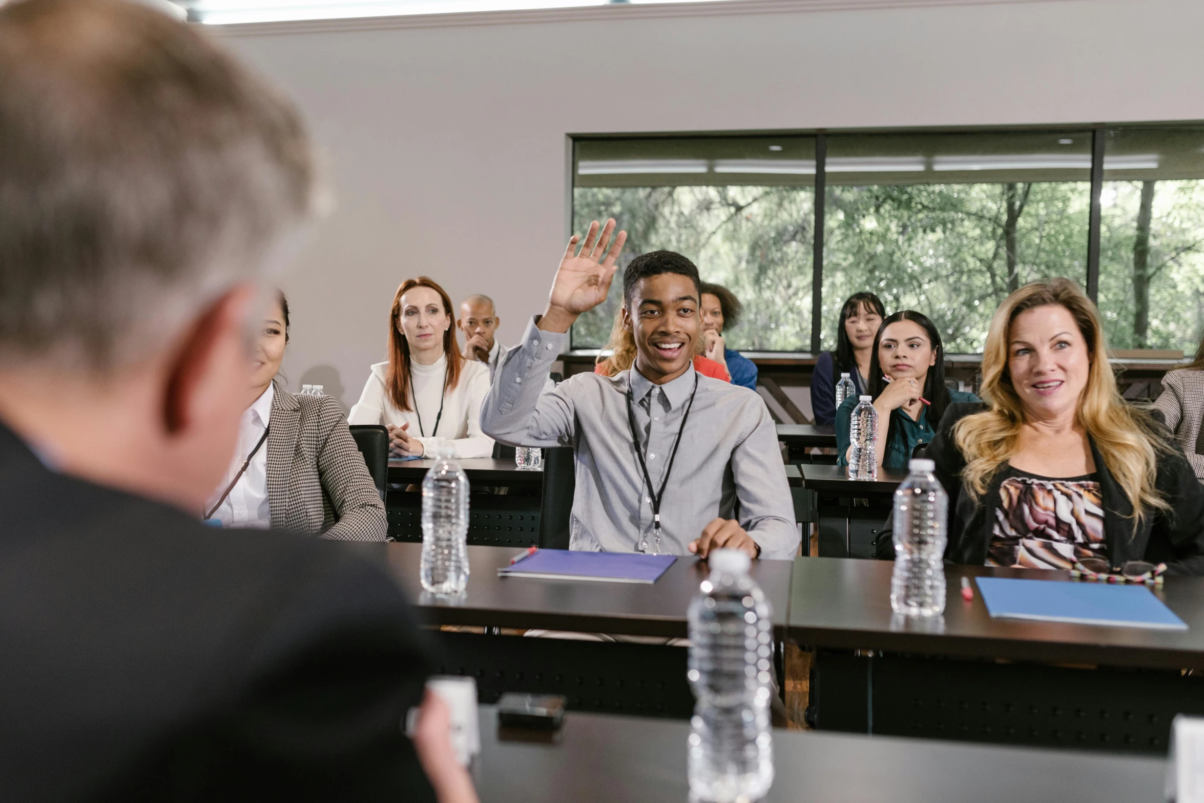 a man giving a presentation to a group of people, by Gavin Nolan, unsplash, academic art, background image, candid portrait photo, raised hand, professional shoot