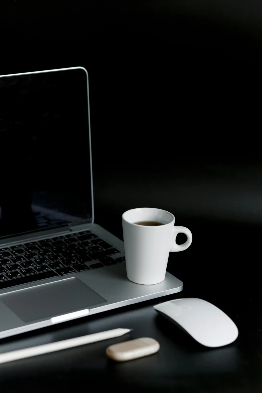 a laptop computer sitting on top of a desk next to a cup of coffee, by James Morris, white on black, no - text no - logo, coffee cups, detail shot