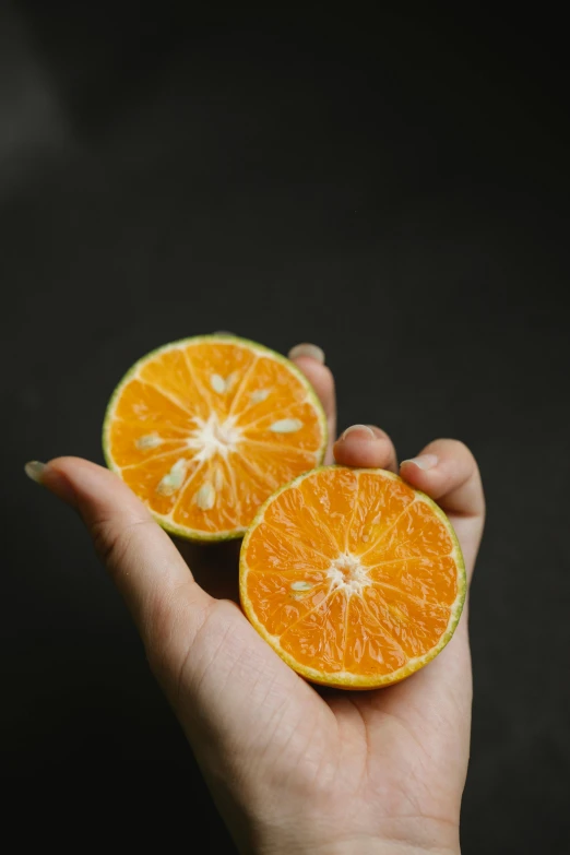 a person holding an orange in their hand, pexels, multiple stories, standing with a black background, made of food, 🐿🍸🍋