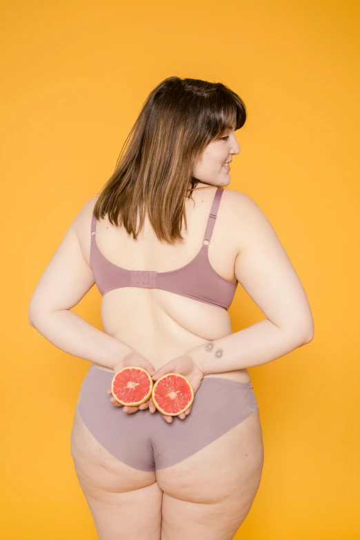 a woman in a bikini and panties holding grapefruits, by Arabella Rankin, figuration libre, overweight, posing together in bra, showing her shoulder from back, non binary model