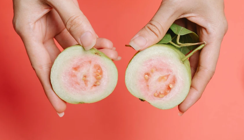 a pair of hands holding a half of a guacamole, an album cover, by Julia Pishtar, trending on pexels, gestation inside a watermelon, cysts, pink skin, tomato