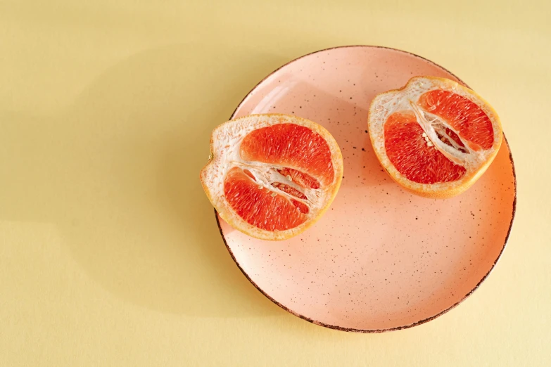 two slices of grapefruit on a pink plate, trending on pexels, hand built ceramics, orange pupils, background image