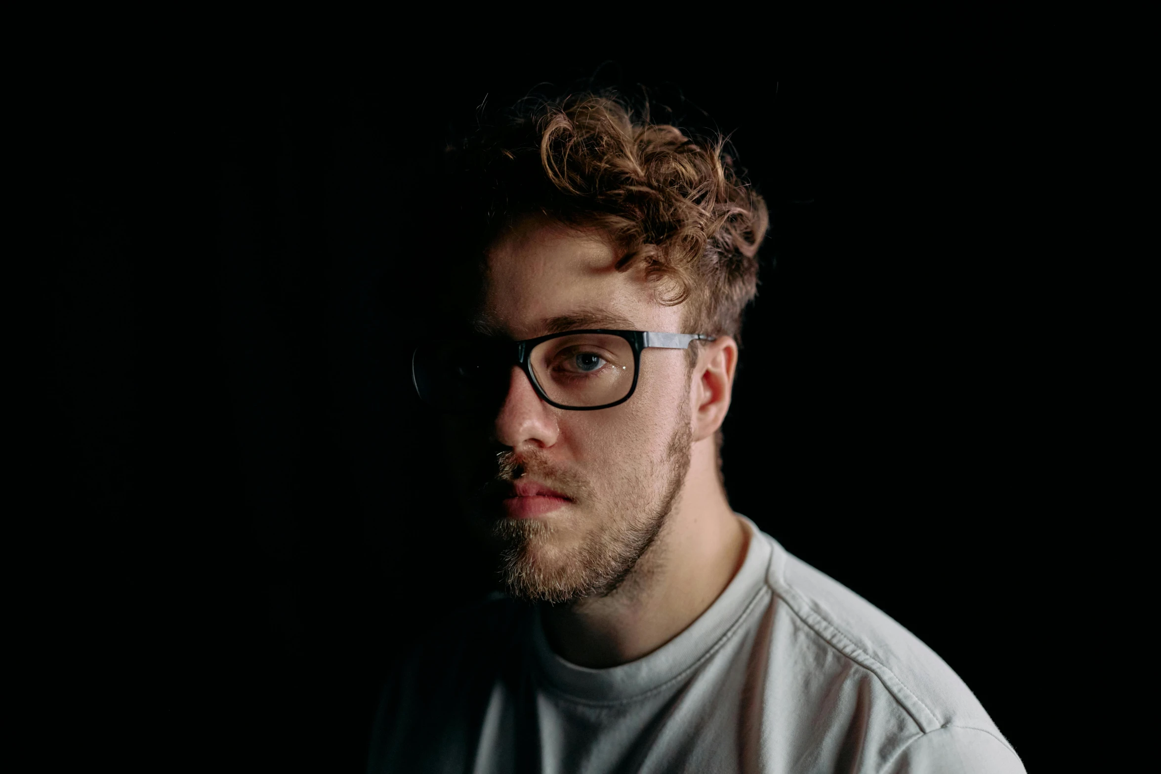 a man with glasses standing in front of a black background, a character portrait, by Jacob Toorenvliet, unsplash, yung lean, low quality photo, sam hyde, on a pale background