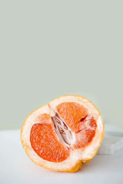 a grapefruit cut in half on a table, trending on pexels, centered in portrait, orange: 0.5, made of glazed, cinematic image