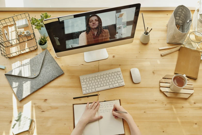 a woman sitting at a desk in front of a computer, trending on pexels, video art, wooden desks with books, close up to the screen, high - angle view, writing a letter