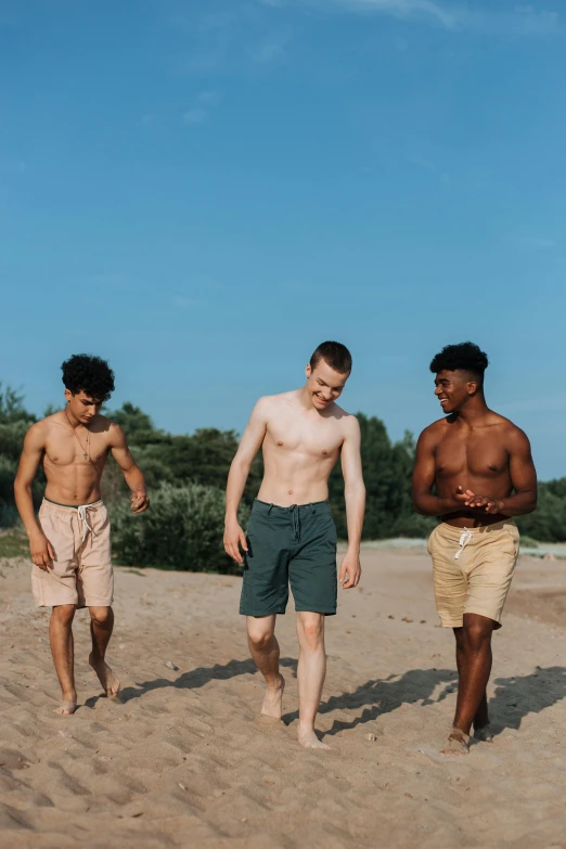 a group of men standing on top of a sandy beach, by Attila Meszlenyi, unsplash, renaissance, tan skin a tee shirt and shorts, two young men, people walking around, lgbtq