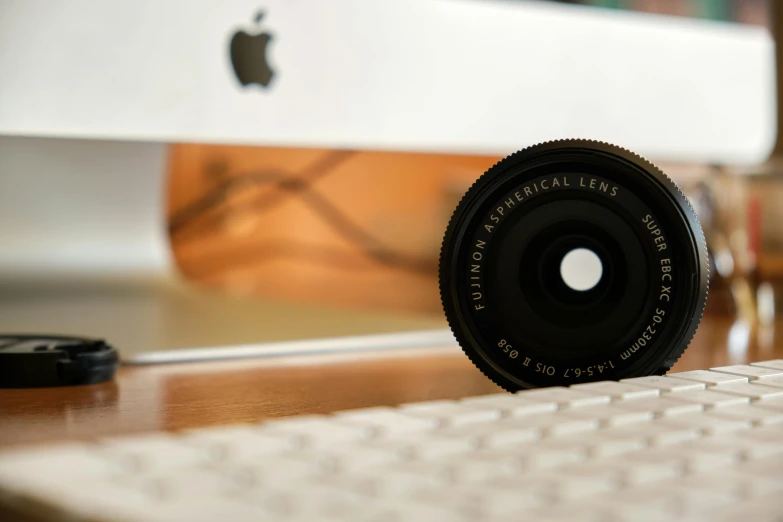 a camera lens sitting on top of a desk next to a keyboard, a picture, unsplash, photorealism, with apple, aperture f 3. 2, leica s photograph, miniature photography closeup